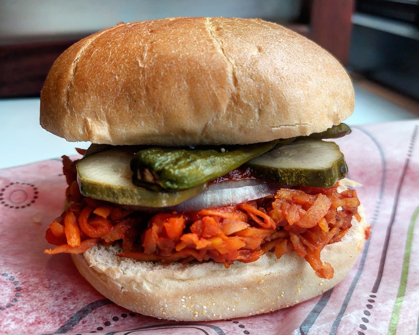 Shredded carrots, cukes, roasted shishitos on bun at Cafe Godot